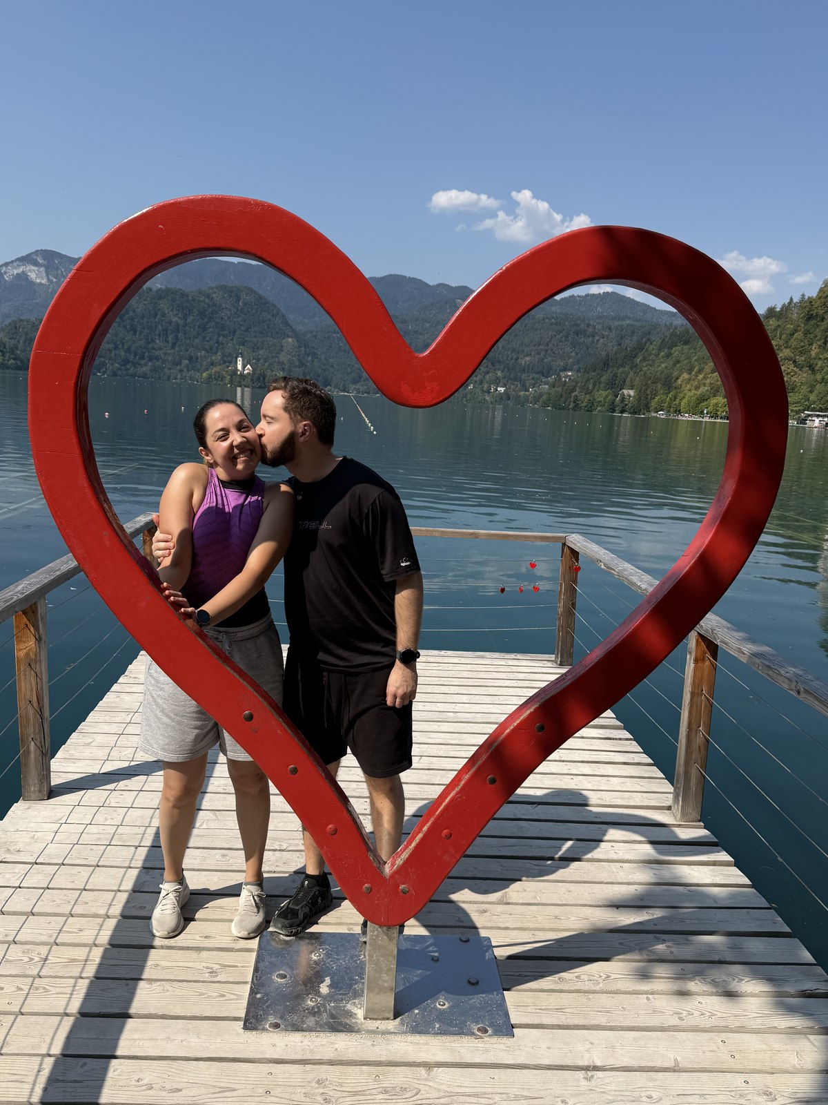 Samira und Luca an einem See, eingerahmt von einer herzförmigen Skulptur